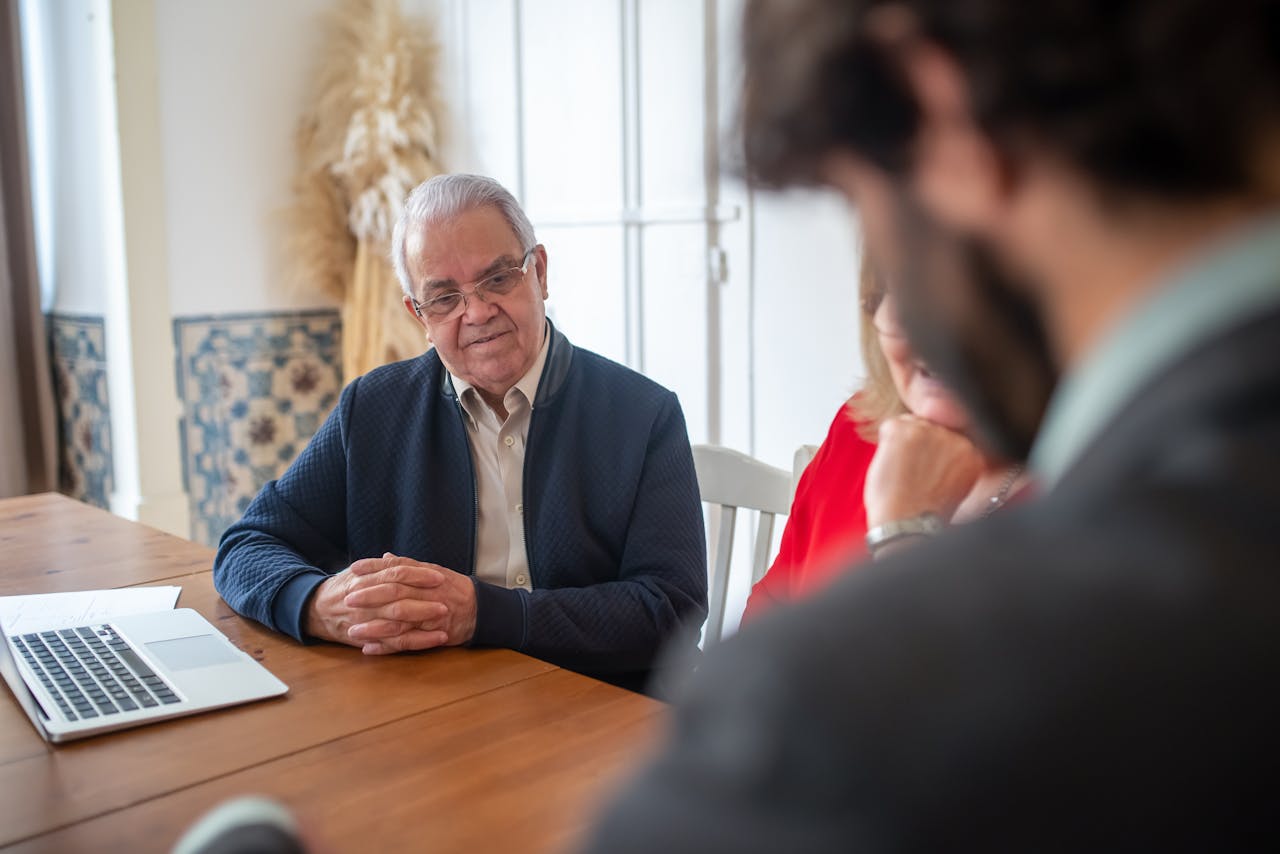 Senior man engaging with consultants at a business meeting indoors.